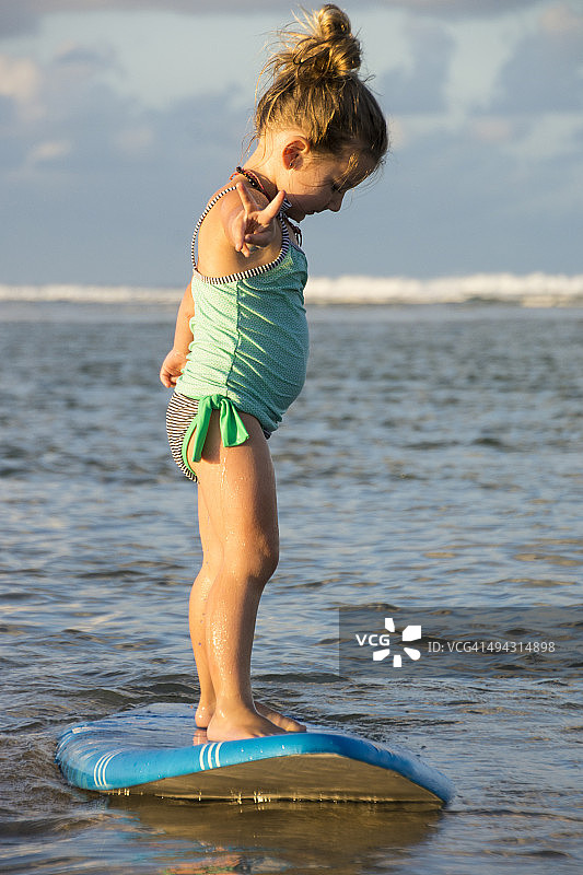 小女孩站在冲浪板上图片素材