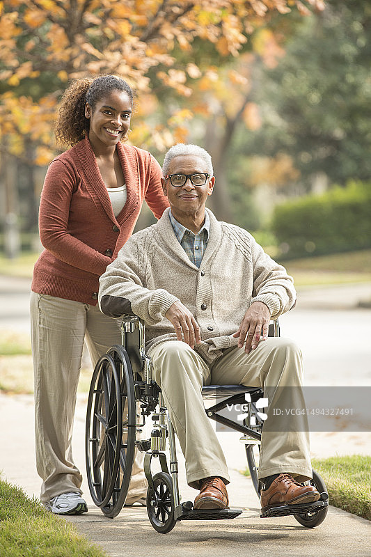 非裔美国妇女推着轮椅上的父亲图片素材