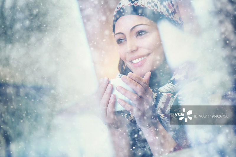 在下雪天喝茶或喝咖啡的女人。图片素材