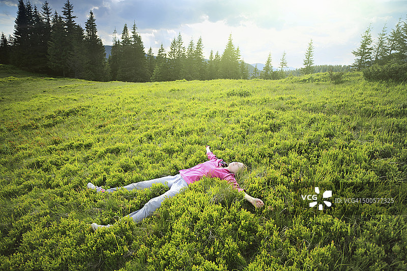 女人躺在山坡的草地上图片素材
