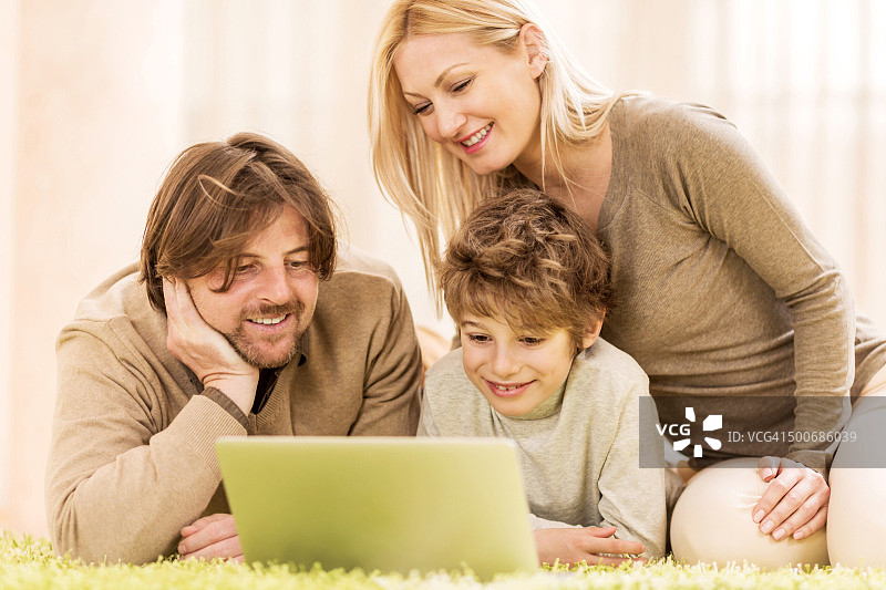 微笑的家人使用笔记本电脑。图片素材