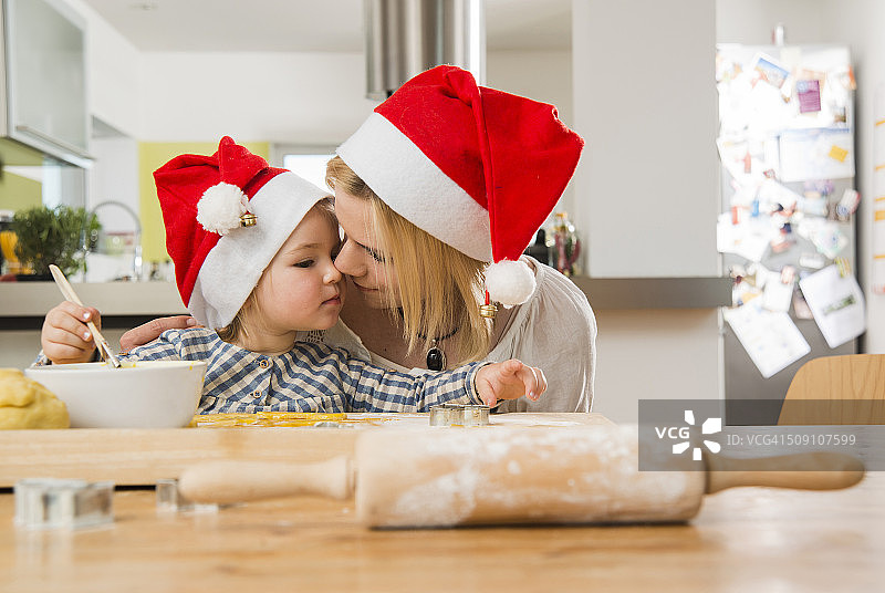 妈妈和女儿戴着圣诞老人的帽子在厨房烘焙图片素材