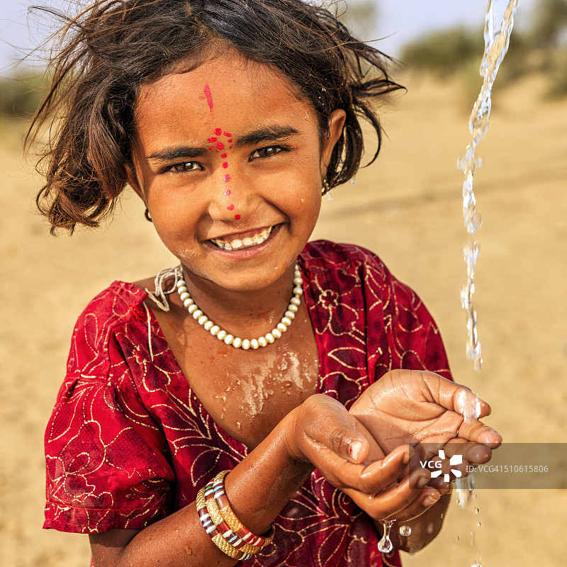 印度拉贾斯坦邦沙漠村庄的一个小女孩喝着淡水图片素材