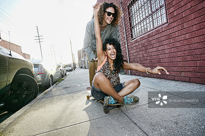 一对夫妇在城市街道上玩滑板图片素材