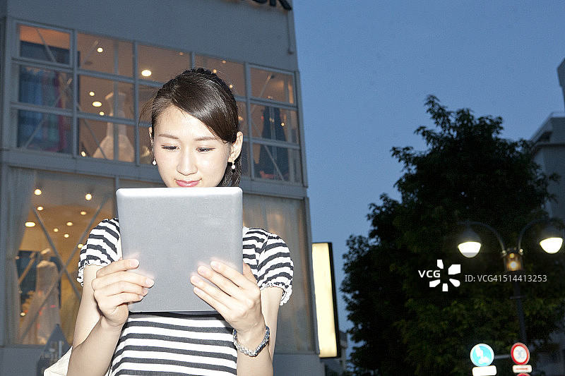一个日本女人在暮色中使用数字平板电脑图片素材