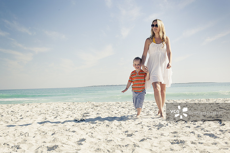 中年成年母亲和年幼的儿子在海滩上散步，开普敦，西开普，南非图片素材