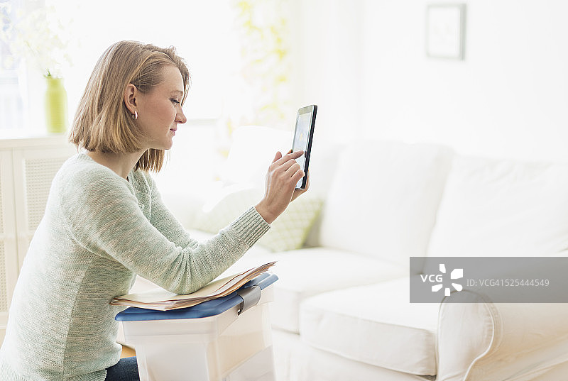 美国，新泽西州，泽西城，坐在客厅里使用数字平板电脑的女人图片素材