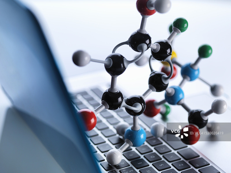 分子模型坐在笔记本电脑键盘上，以说明科学教育和计算机辅助研究图片素材