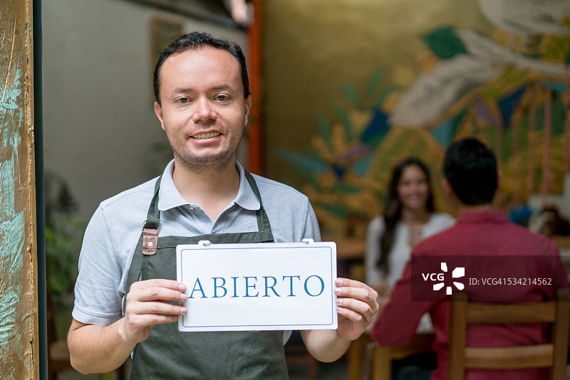 一名男子在餐馆用西班牙语举着营业标牌图片素材