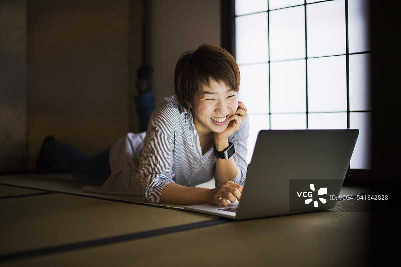 在日本榻榻米上用笔记本电脑的女人图片素材