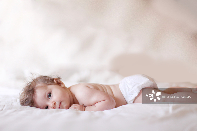 女婴躺在床上，看着摄像机图片素材