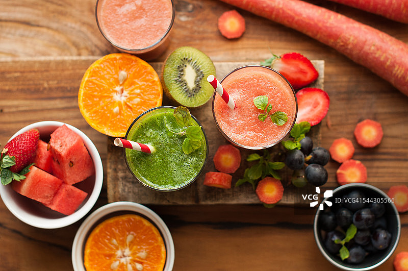 俯视图的各种果汁，如西瓜，绿色果汁在一个木制的背景图片素材