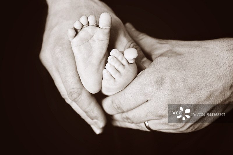婴儿的脚在她父亲的手中图片素材