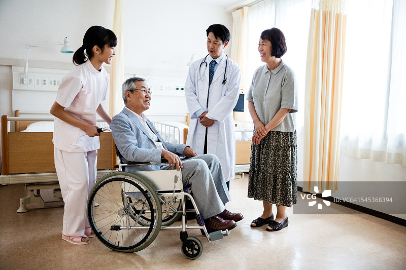 老人坐在轮椅上，医生和女士站着图片素材