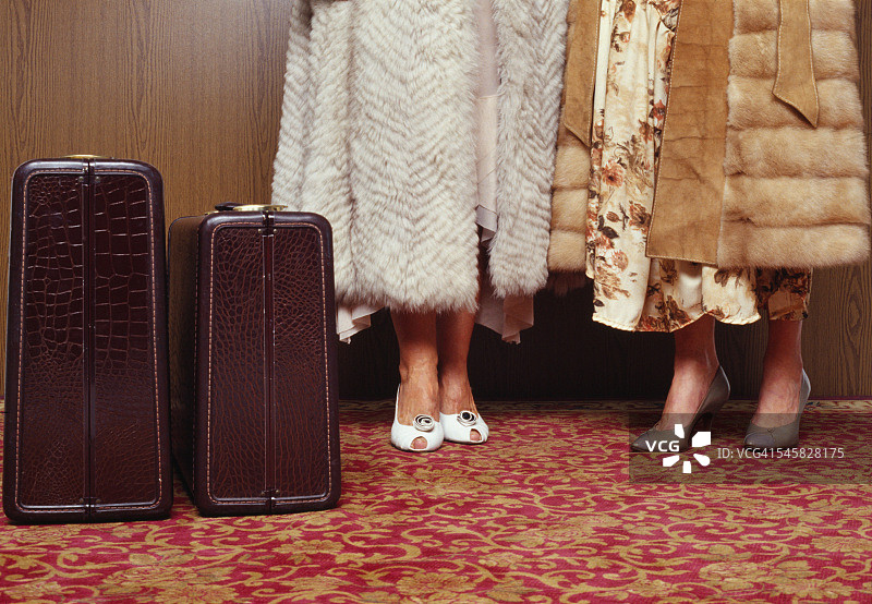 穿着皮草大衣的女人站在手提箱旁边图片素材