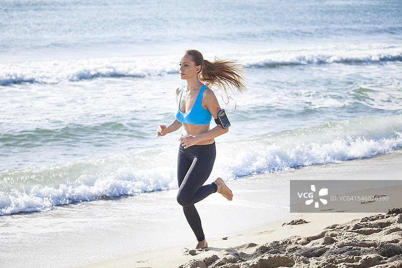 年轻女子在海滩上慢跑图片素材