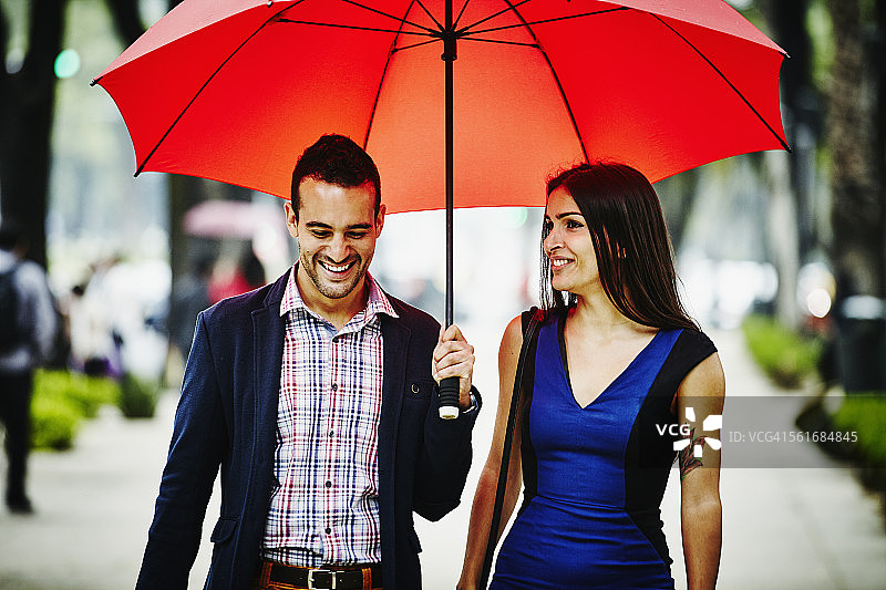 微笑的情侣在伞下散步图片素材