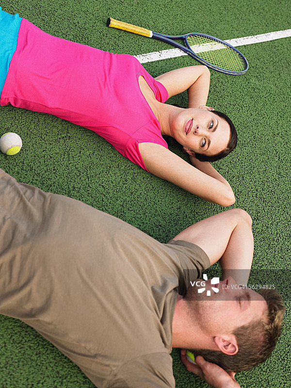 一对年轻夫妇躺在网球场上图片素材