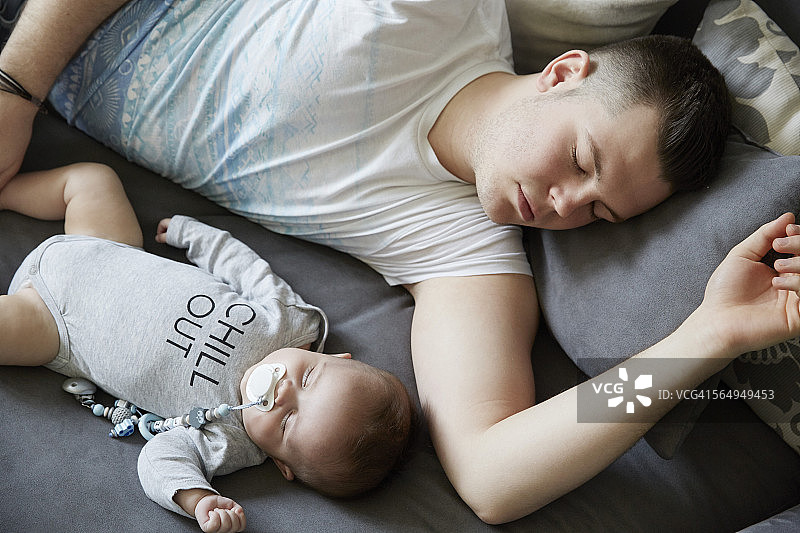 年轻的父亲和婴儿睡在沙发上图片素材