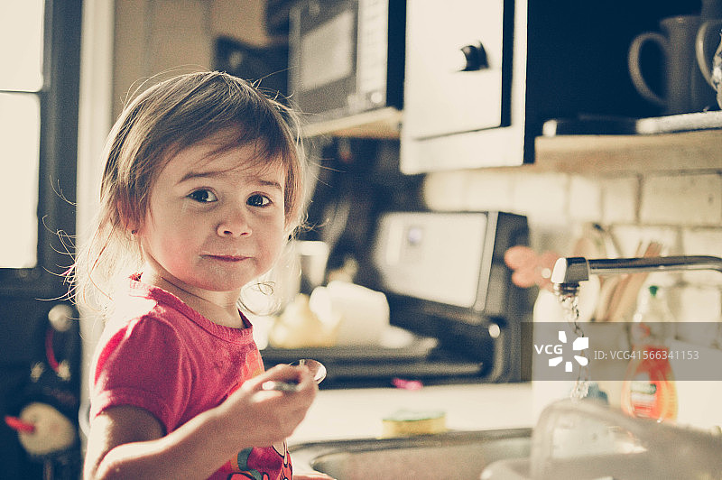 小女孩在厨房水槽边。图片素材