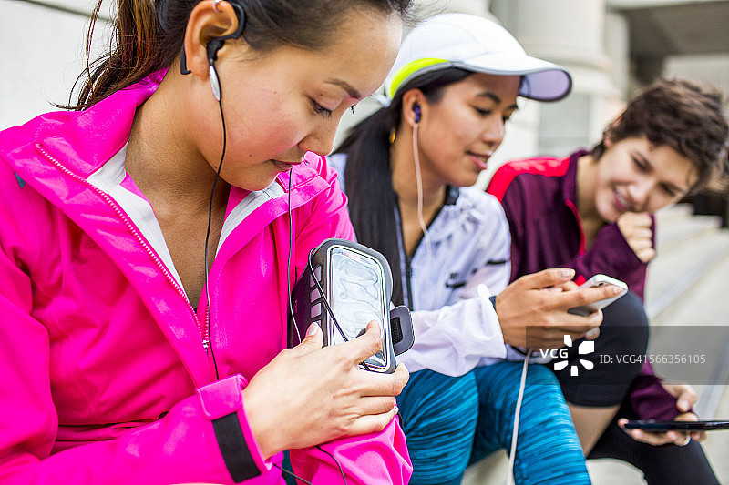 跑步者在城市人行道上使用手机和耳机图片素材