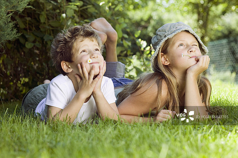 男孩和女孩(6-9)躺在草地上，向上看图片素材