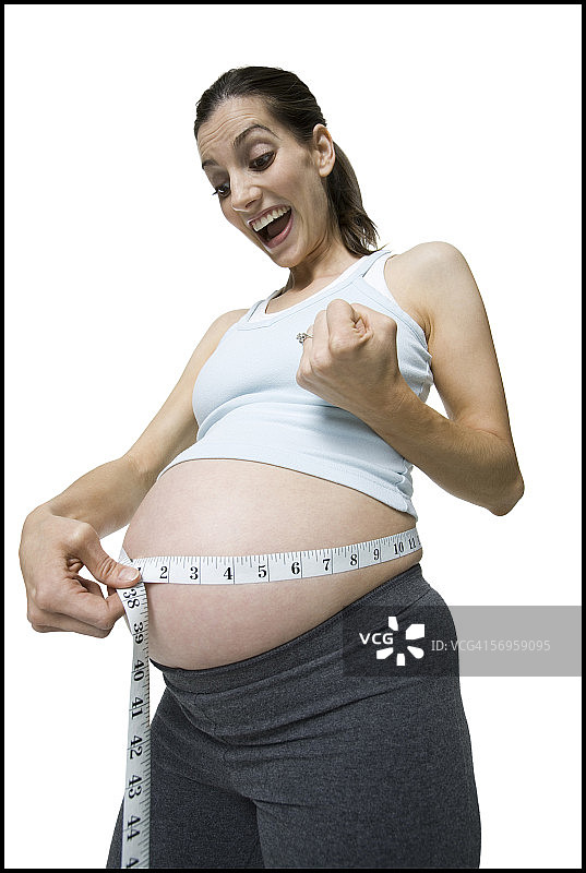 一个孕妇的特写镜头测量她的腹部用测量尺图片素材