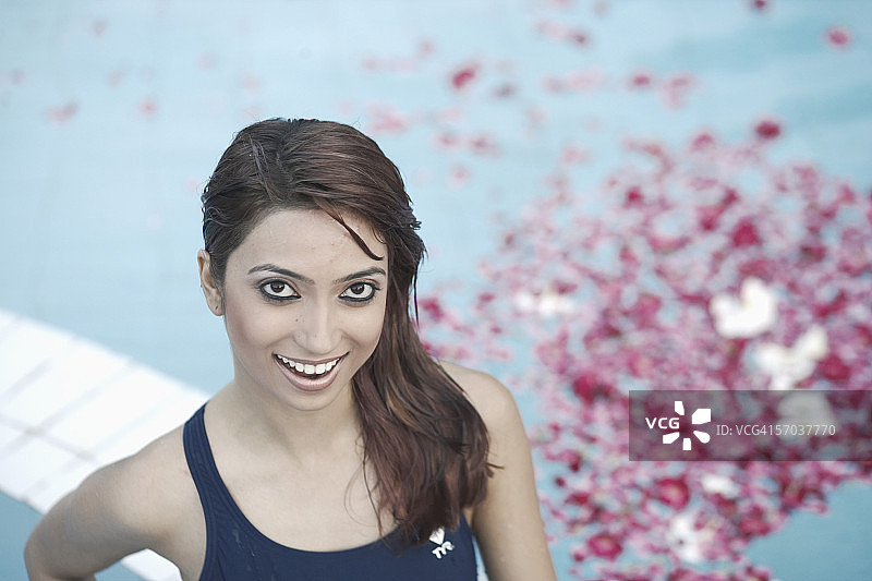 高角度的一个年轻女子站在一个充满花瓣的游泳池图片素材