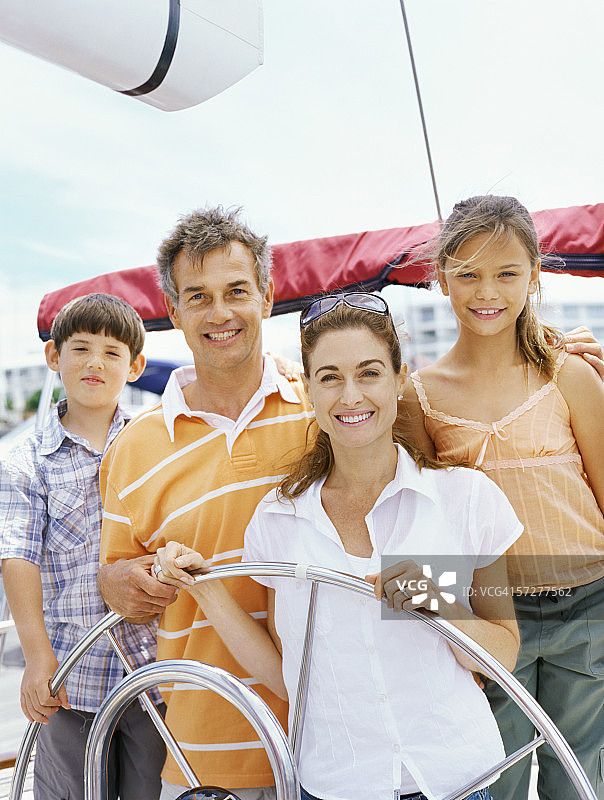 一家人微笑着驾驶着一艘帆船图片素材