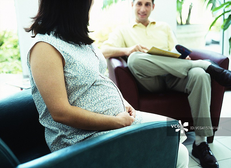 侧面特写的孕妇坐在椅子上和她的丈夫说话图片素材