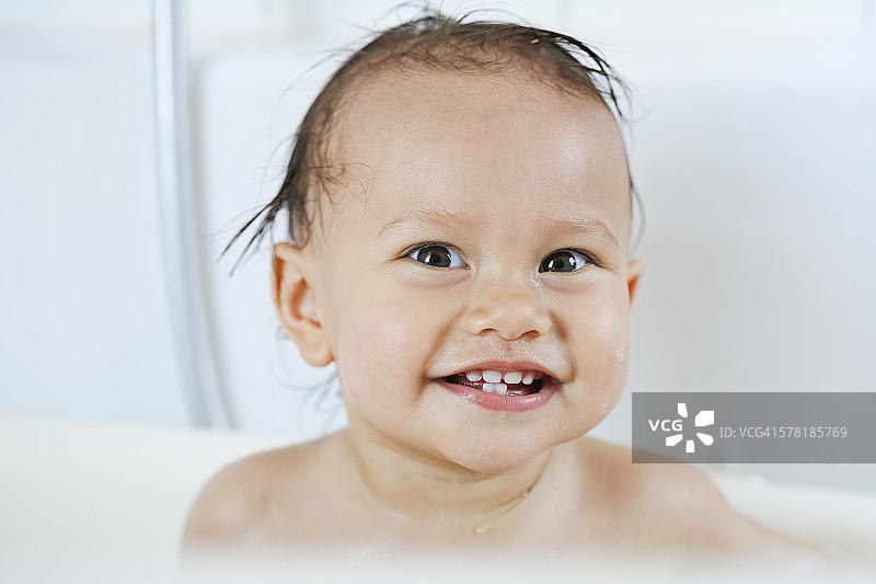 在浴缸里微笑的女婴的肖像图片素材