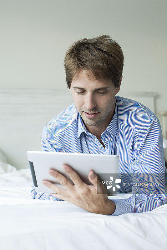 男人躺在床上用平板电脑图片素材