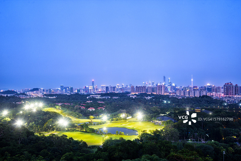现代城市的天际线和夜间的高尔夫球场图片素材