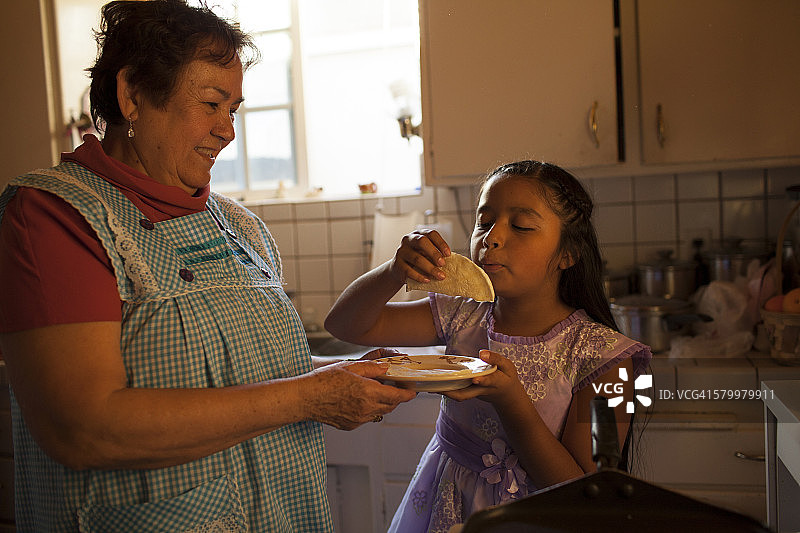 西班牙妇女在厨房为孙女做饭图片素材