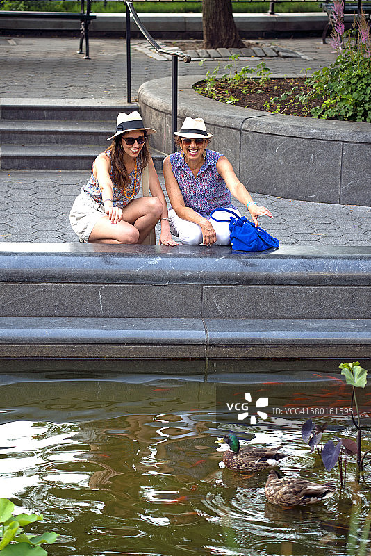 拉丁美洲妇女享受公园池塘，纽约。图片素材