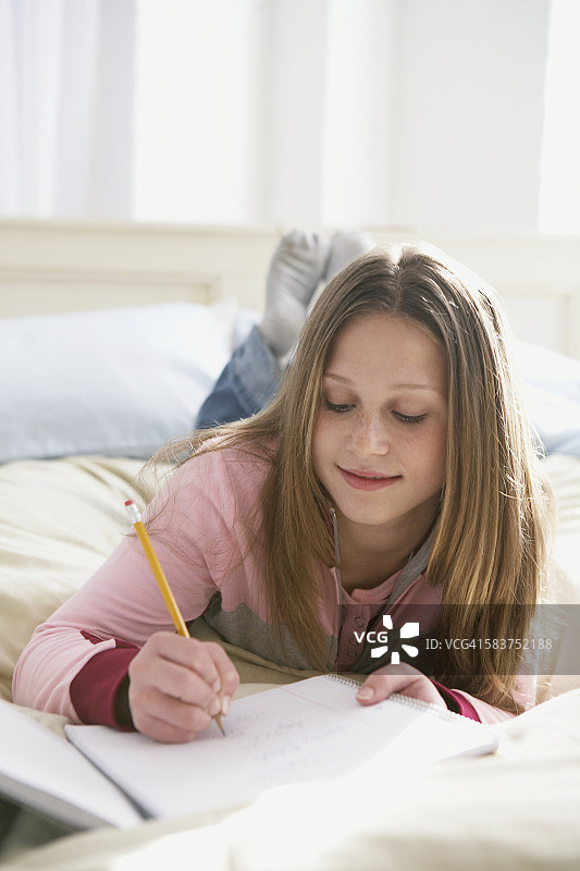 女孩在床上做作业图片素材