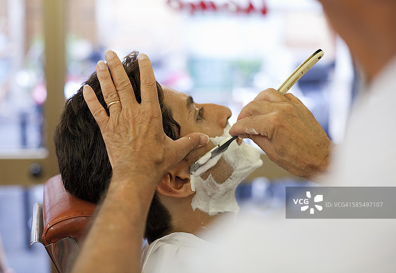 一个男人在理发店湿着脸刮胡子图片素材