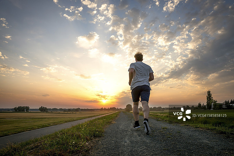 男子在日落慢跑的后视图图片素材