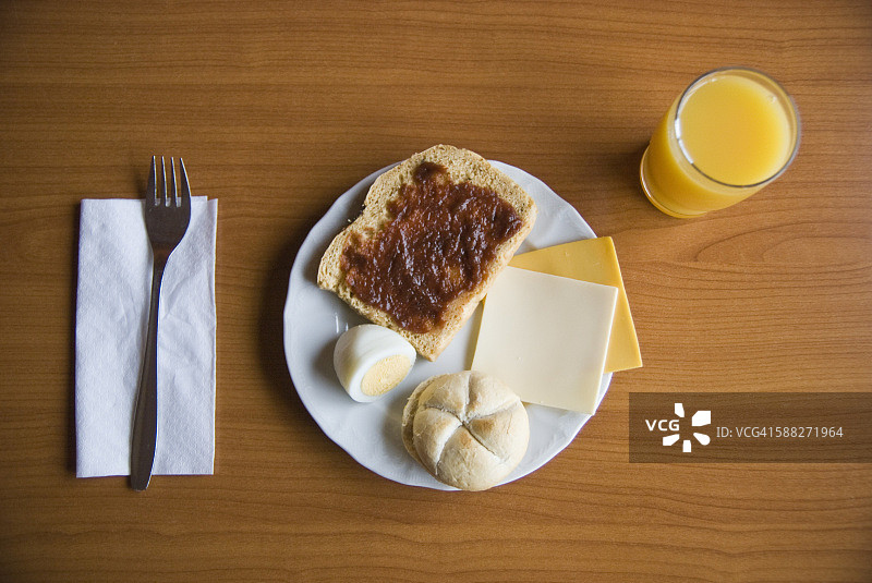 早餐有果酱吐司、煮鸡蛋、面包卷、奶酪和橙汁图片素材