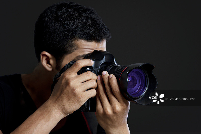 男性摄影师在黑色背景下拍照的特写图片素材