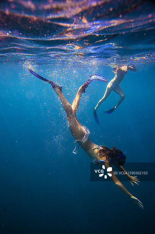 两个年轻女子浮潜在海洋。图片素材