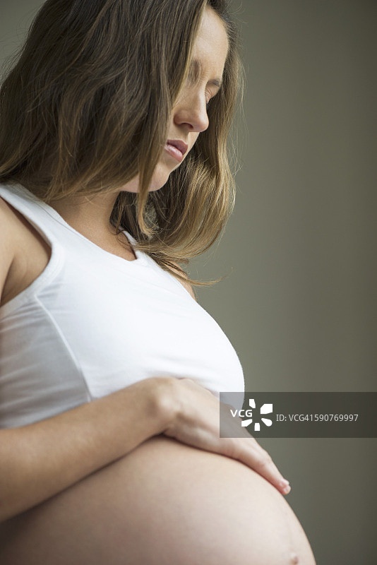 女人爱抚着怀孕的肚子图片素材