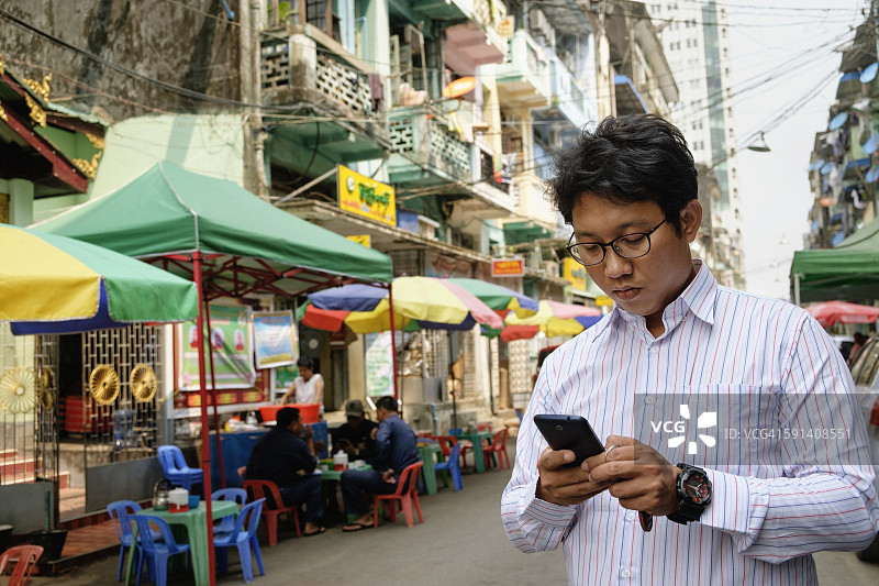 亚洲商人在城市里使用手机图片素材