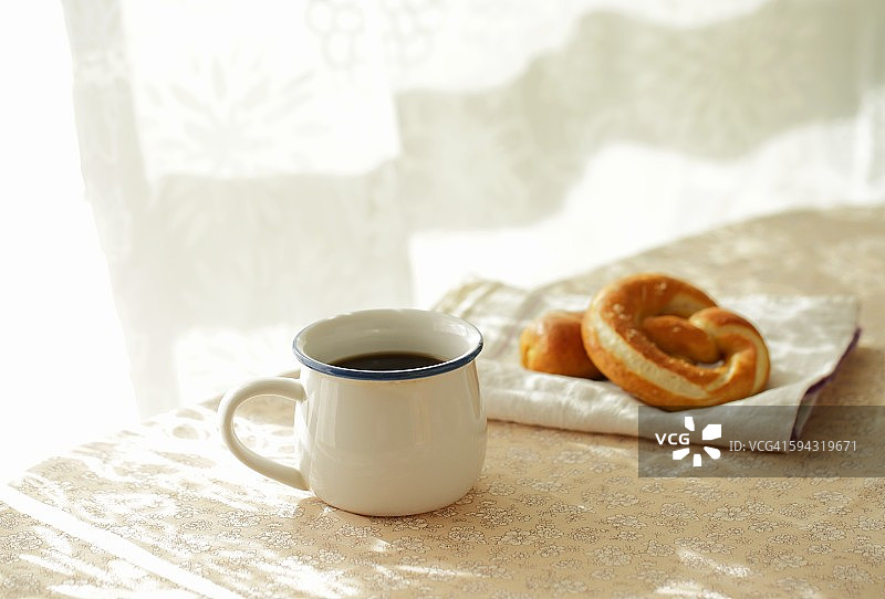 桌上放着咖啡和软椒盐卷饼面包图片素材