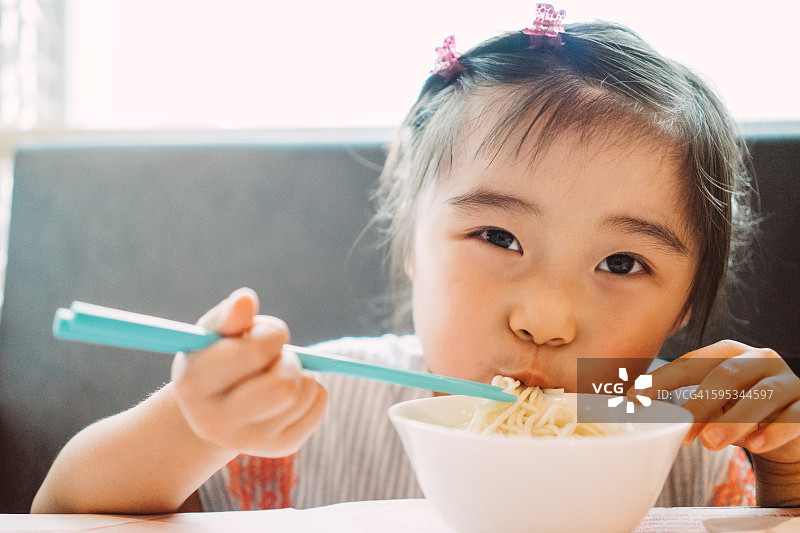 小女孩用筷子吃面条图片素材