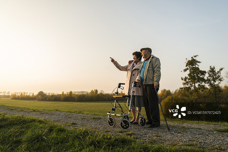 一对老年夫妇拄着拐杖和轮式步行者站在大自然中图片素材