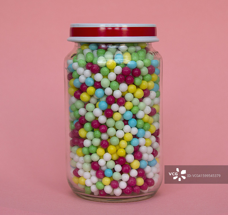 粉红色背景下装满糖果的罐子图片素材