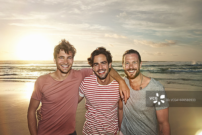三个男性朋友在海滩上微笑着图片素材