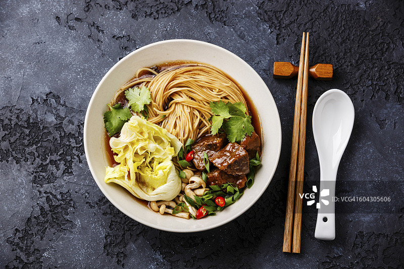 辣的亚洲面条肉汤与牛肉在深色背景图片素材