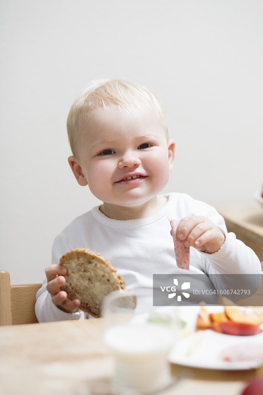 小男孩吃早餐，面包卷和香肠图片素材